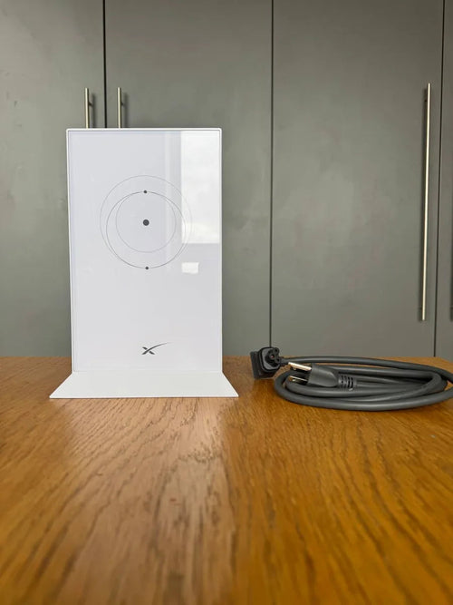 Starlink Gen 2 Wi-Fi router standing upright on a wooden table beside its coiled AC power cord.