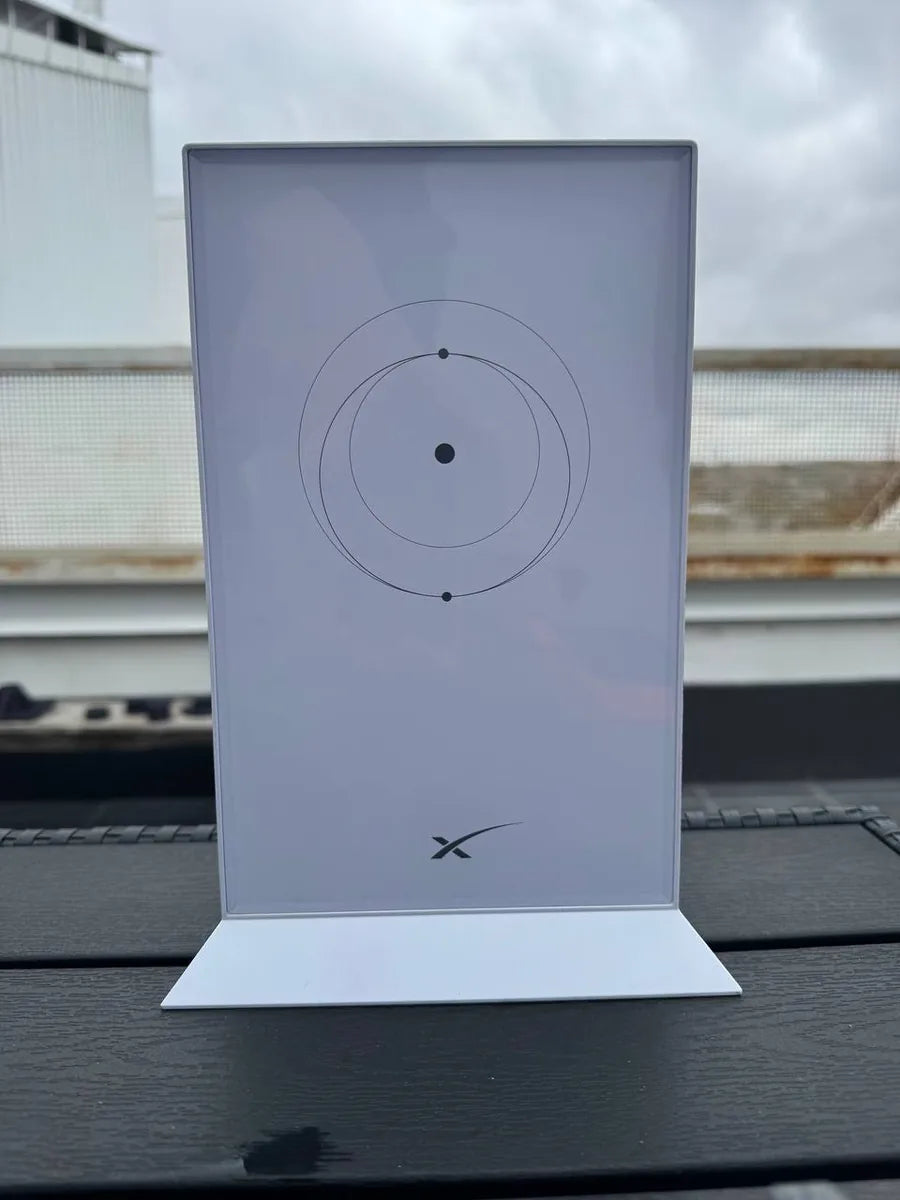 Close front view of the Starlink Gen 2 router on a dark deck table, showing the clean white face.