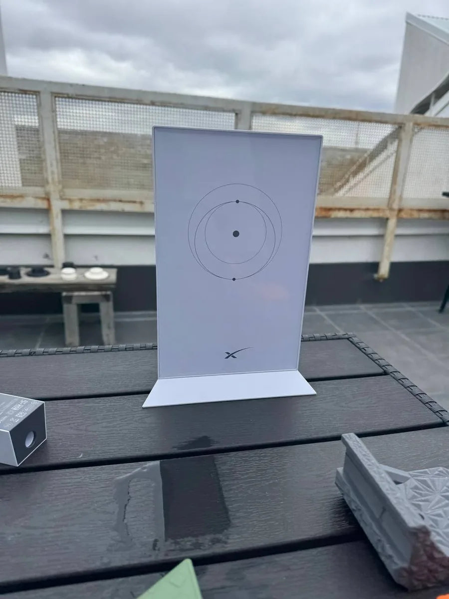 Starlink Gen 2 router upright on an outdoor deck table under an overcast sky, wide context view.