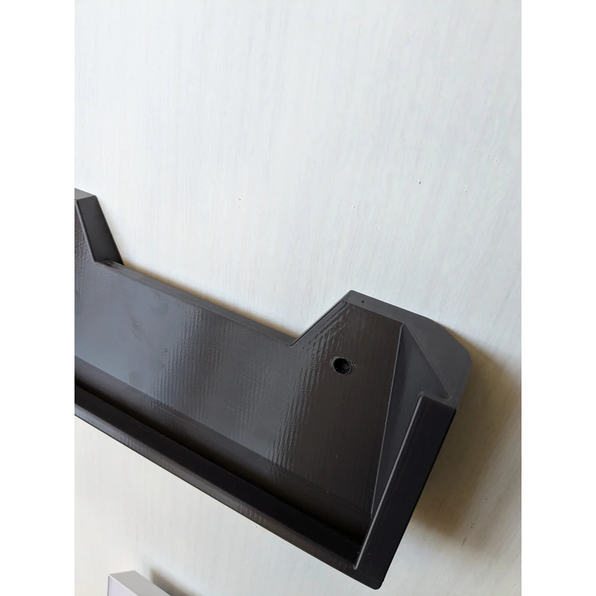 Angled view of the empty StarMax bracket on the wall, showing the cradle and printed finish.