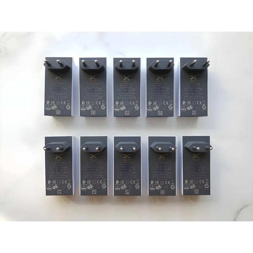 Ten Starlink Mini power supply units, EU plug versions, laid out top-down on a white surface.