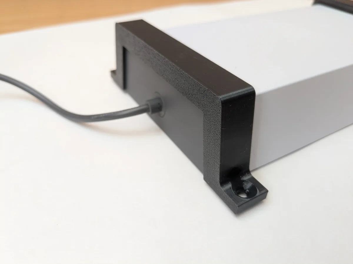 Black StarMax bracket clamped onto the end of the Starlink power supply, cable exiting alongside.