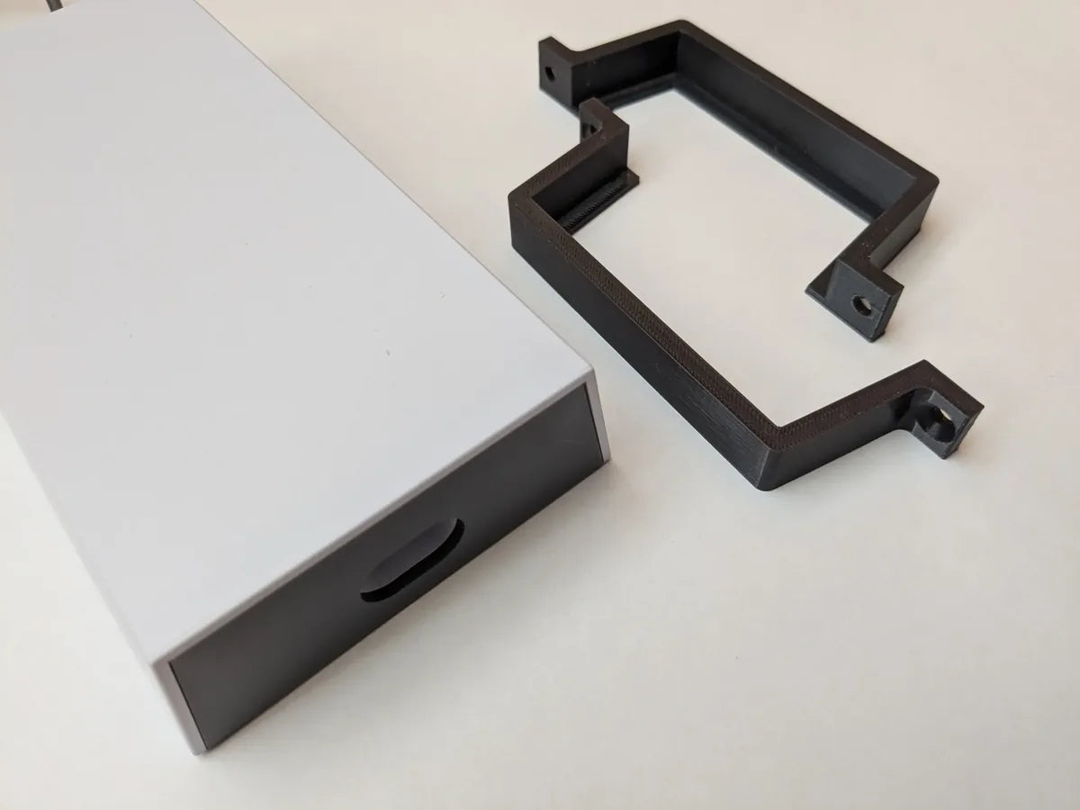 Starlink power supply body next to the black StarMax 3D-printed wall mount bracket, angled view.