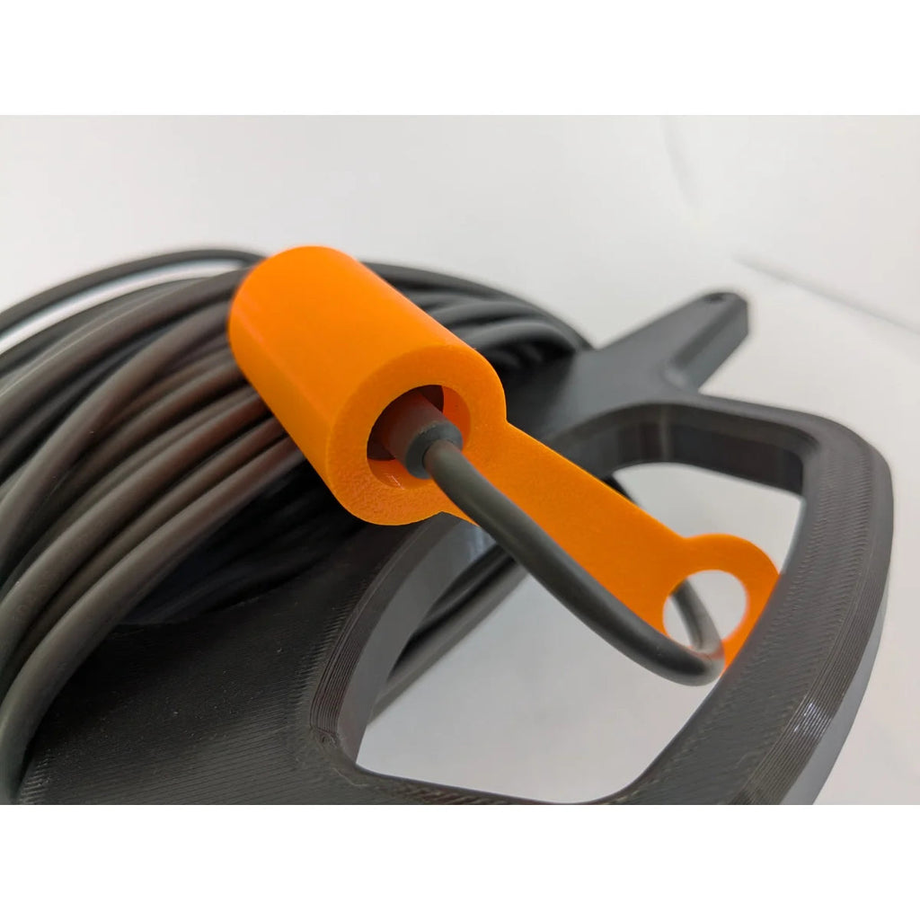 Orange 3D-printed connector cap and retaining clip on the StarMax cable caddy, holding the cable end.
