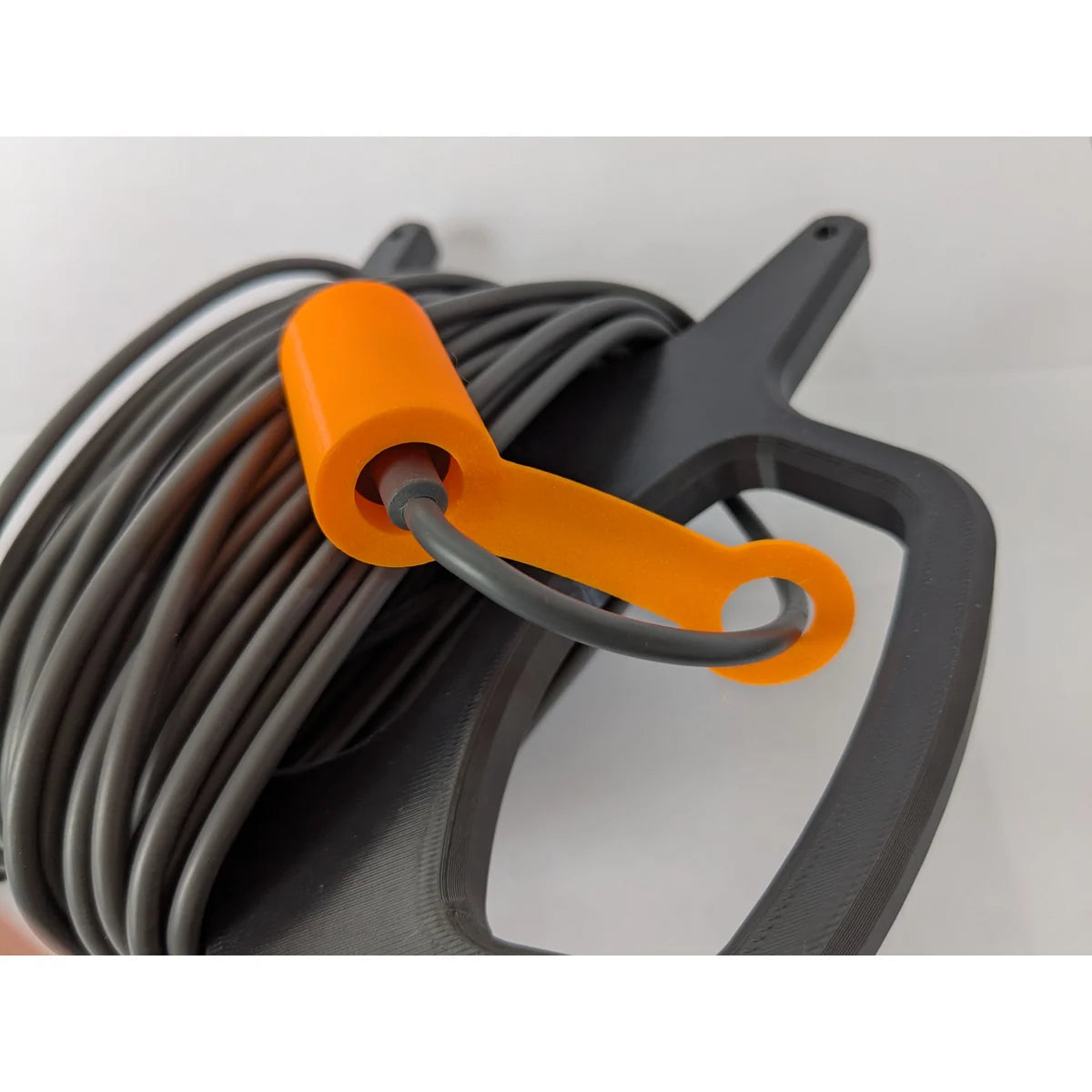 StarMax 3D-printed cable caddy holding a coiled cable, with the orange connector cap clipped in place.