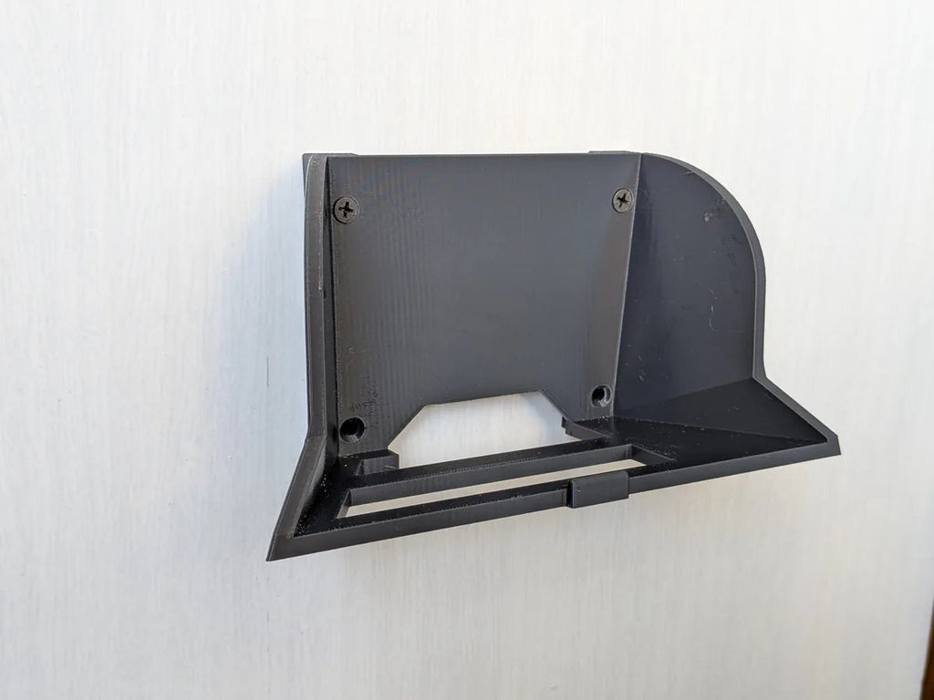 Angled view of the black StarMax wall bracket fixed to a wall, showing the cradle and screw points.