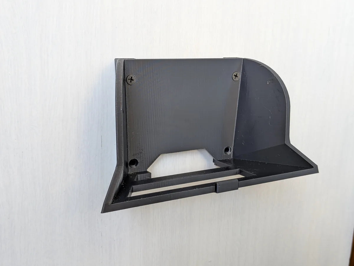 Angled view of the black StarMax wall bracket fixed to a wall, showing the cradle and screw points.