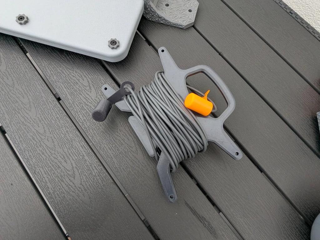 StarMax 3D-printed cable caddy holding a neatly coiled Starlink cable with an orange retaining clip.