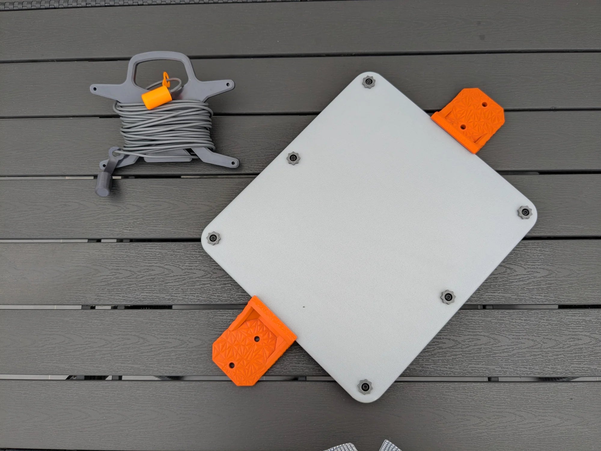 StarMax armor case for Starlink Mini fitted with orange mounting brackets, cable caddy beside it.