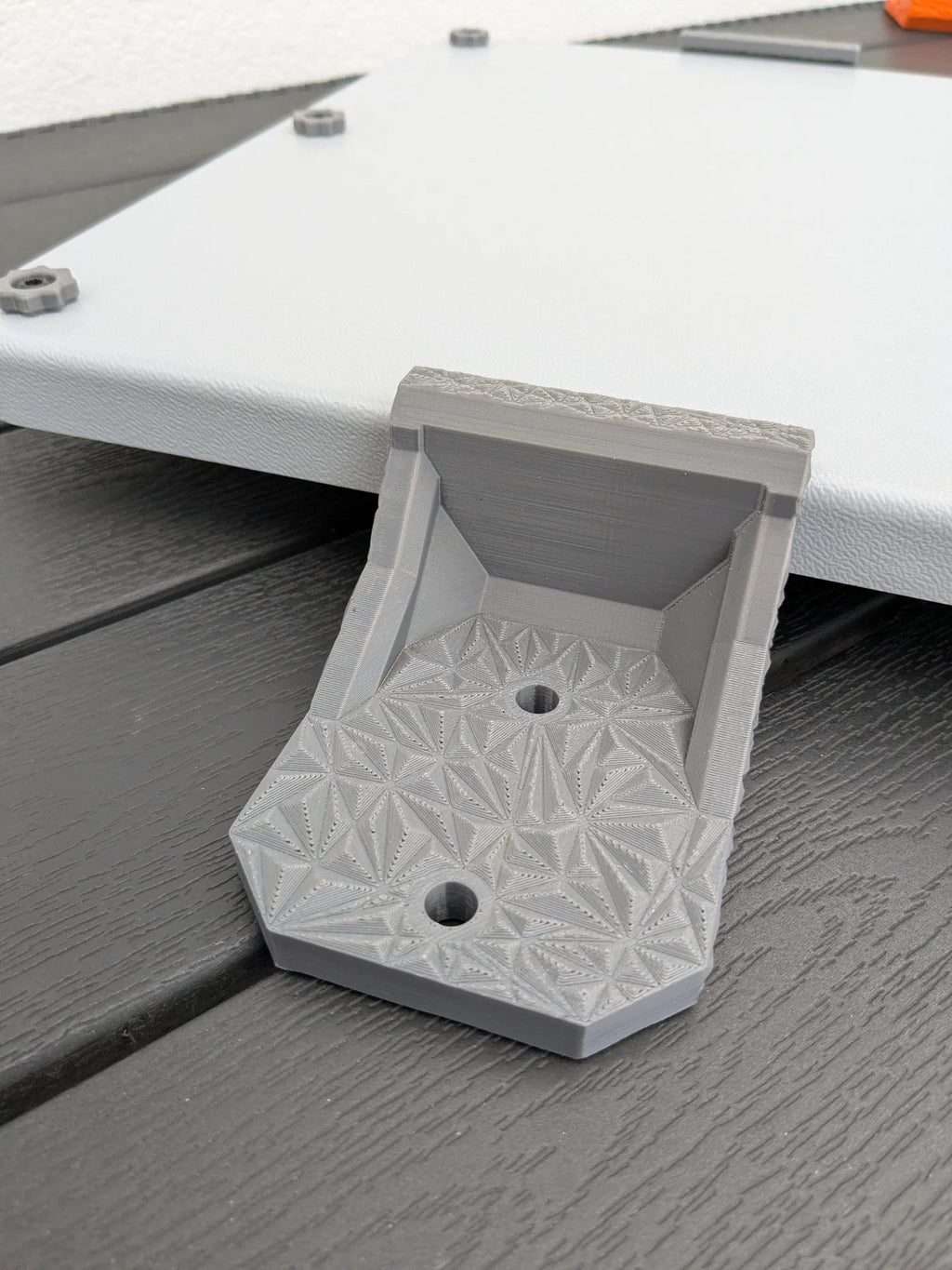 Close-up of a single grey StarMax Starlink Mini mounting bracket with textured surface and two bolt holes.