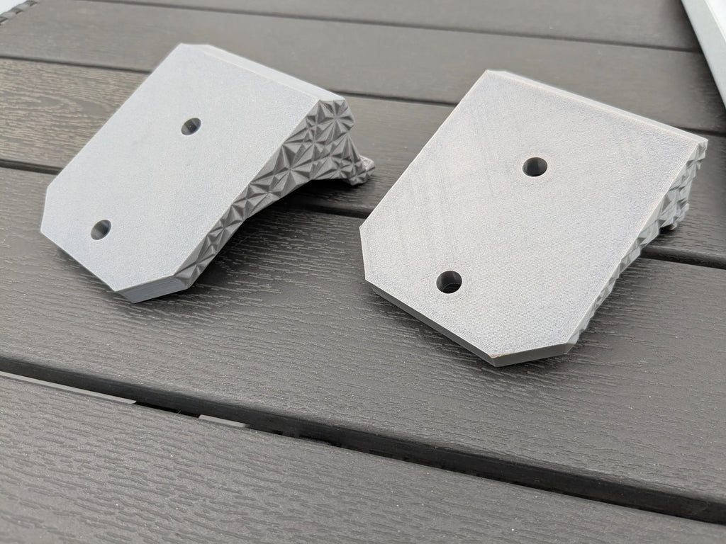 Close-up of two StarMax Starlink Mini brackets showing the twin round fixing holes in each mounting foot.